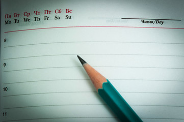 a simple green pencil is lying on the notebook, plans, with a vignette.