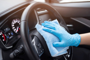 car wash,  worker hand wear glove cleaning console steering wheel with microfiber cloth blue. hygiene prevention  antibacterial of corona virus outbreak.