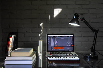 Home office desk with midi keyboard, notebook and books. 
