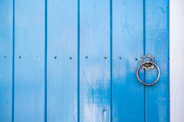 Close-up of a newly painted wooden entrance door, part of a renovated cottage. Showing the fresh blue gloss paint and traditional latch.