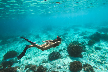 Woman snorkelling underwater with snorkel mask in clear transparent water in beautiful tropical lagoon with coral reef. Freediving activity. Leisure on vacations.