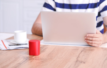 Young man with smart home assistant device in kitchen