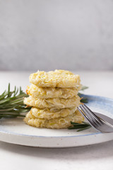 Zucchini pancakes. Fork and light plate. Light background. Green zucchini