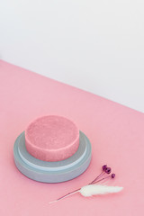 Round pink moisturizing soap in a concrete soap dish on a pink background. Top view.