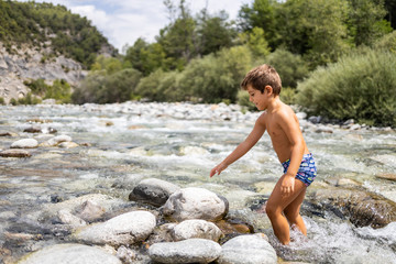 Little child in the middle of a wild river