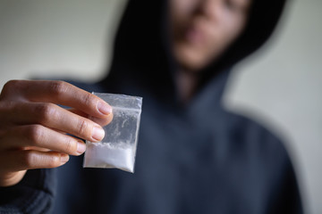 Hand of addict man holding cocaine or heroine, close up of addict buying dose from drug dealer, drug trafficking, crime, addiction and sale concept, - obrazy, fototapety, plakaty