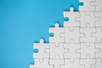 White jigsaw puzzle pieces on a blue background. Problem solving concepts. Texture photo with copy space for text