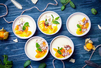 Obraz na płótnie Canvas Homemade dessert panna cotta with mango sauce, winter cherries, mint, white chocolate on a dark background