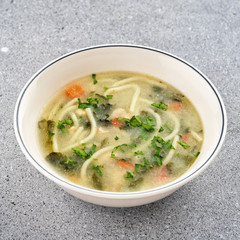 Noodle soup with chicken broth, parsley and carrots.