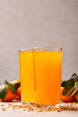 Two glasses with fresh orange juice.Juice with nuts on the background. Light background. Tangerines and oranges on the background. Green leaflet. Drinks for a healthy diet