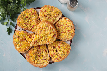 Hot sandwiches with cheese and sausage in a plate on light blue background, Horizontal format, Top view, Space for text