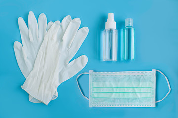 Medical hygienic items on blue background. Surgical gloves, medical face mask, alcohol hand gel and alcohol spray. Protection COVID-19, Coronavirus spread. Healthcare concept. Top view, flat lay