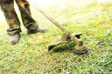 Young man mows the grass on the lawn with a trimmer.