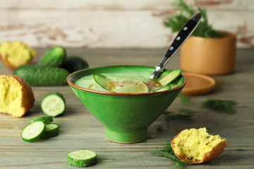 Bowl with cold cucumber soup on table