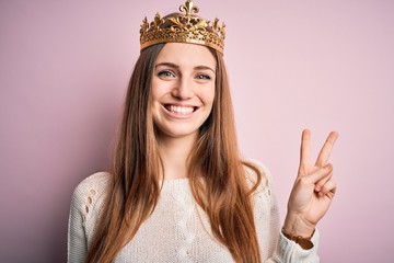 Young beautiful redhead woman wearing queen crown over isolated pink background smiling with happy...