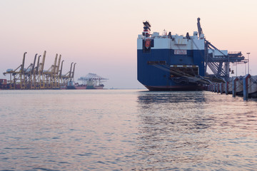 Obraz premium Huge container cargo ship on harbor while load car into it
