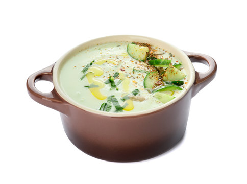 Pot with cold cucumber soup on white background