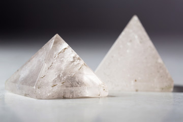 Two natural rock crystal pyramids against a dark background