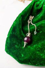 Natural stone pendulum on green velvet