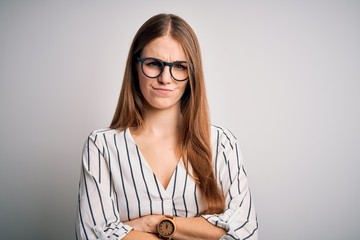 Young beautiful redhead woman wearing casual striped t-shirt and glasses skeptic and nervous,...