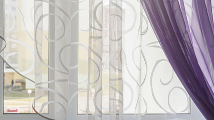 Obraz premium white and purple curtain with rounded edge and swirling lines hangs on window