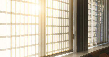 large window with windowsill and beige textile shutters with hard sunlight