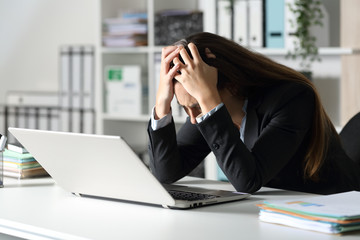 Sad executive complaining on her desk at the office
