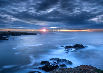 Sunset time at the Mendocino Headlands State Park, Northern California, USA, featuring predominantly blue colors and some clouds with lots of copy space and lens flare