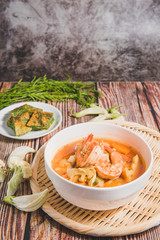 Mixed shrimp curry in a white bowl on a wooden background.