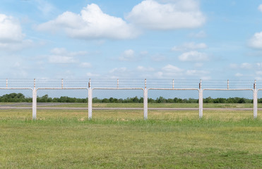 Outdoor background of grass field and fence area with blue sky and white clouds.