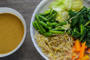 Pecel before mixing, indonesian traditional food made from various boiled vegetables such as carrots, bean sprouts, cabbage, long beans, mustard greens served with peanut sauce.