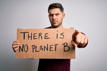 Young activist man holding protest banner for climate change and environment change pointing with finger to the camera and to you, hand sign, positive and confident gesture from the front