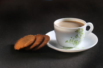 A ceramic cup of red tea served with butter cookies biscuit on the black background selective focus with on subject and  surface.  Isolated. 