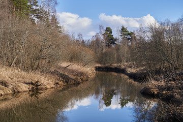 A winding river with steep banks, dry grass and trees