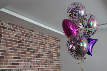 Purple star, pink heart and transparent balloons with colorful confetti filled with helium. The concept of decorating a room with helium balloons for holidays or 