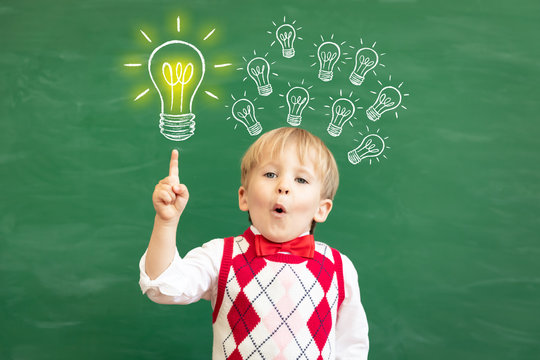 Bright idea! Happy child student against green chalkboard