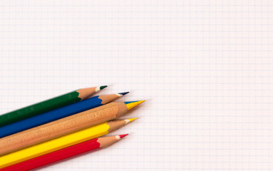 Lápices de colores sobre fondo de hoja cuadriculada. 