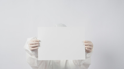 Female model wearing PPE suite and Hand with gloves is holding A4 paper on white background.