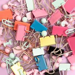 Texture made of paper clips and push pins on a pink pastel background.