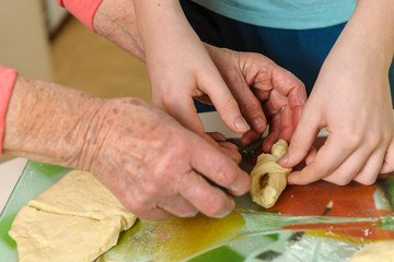 Grandmother teaches grandson how to bake homemade cookies. Hands close-up, sharpness on the hands of a boy.