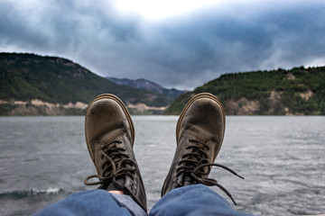 Dirty boots in front of a mountainous lake