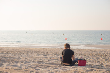 Faceless girl reads alone on the beach. Concept of loneliness