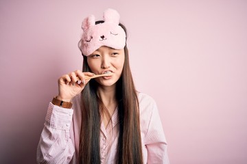 Young beautiful asian woman wearing pajama brushing her teeth using tooth brush and oral paste, cleaning teeth and tongue as healthy health care morning routine