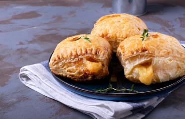 Puff buns with cheese on the ceramic plate with herbs around