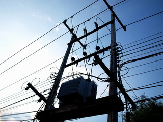 The silhouette of the electric transformer on the pole On the background of the evening blue sky....