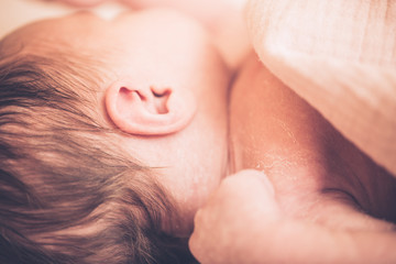 Fototapeta premium Newborn baby boy lying on bed, sleeping, close up. Healthy newborn baby sleeping, showing close up of ear and side of babies head.