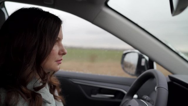Brunette woman driver behind the steering wheel driving her crossover suv car