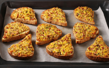 Homemade hot sandwiches with cheese and sausage, on parchment on a baking tray, Horizontal format, closeup