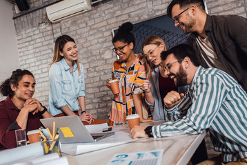 Group of modern business people in casual wear discussing architectural designs while sitting in the creative office.