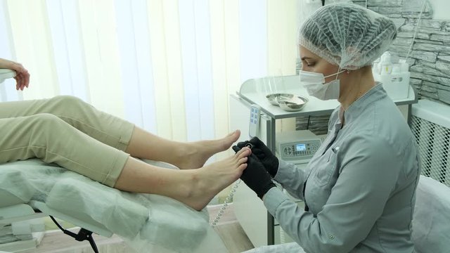 Podology. Hardware pedicure. The podologist treats the patient&rsquo;s toenails.